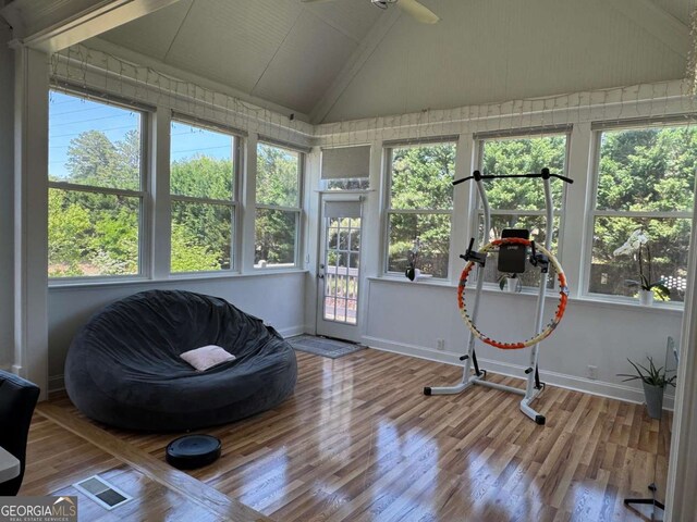 sunroom with baseboards, vaulted ceiling, a wealth of natural light, and wood finished floors