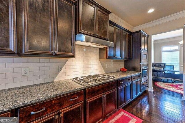 kitchen featuring light stone countertops, decorative backsplash, dark wood-type flooring, crown molding, and stainless steel gas stovetop