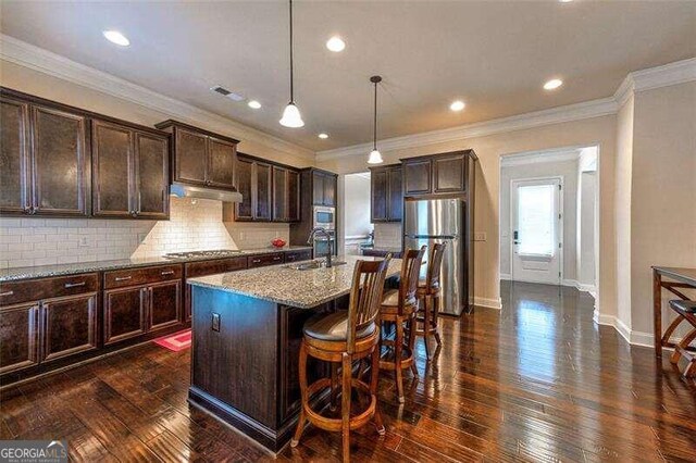 kitchen featuring light stone counters, a kitchen island with sink, stainless steel appliances, sink, and dark hardwood / wood-style flooring