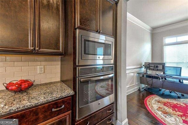 kitchen with appliances with stainless steel finishes, light stone countertops, crown molding, and dark hardwood / wood-style floors