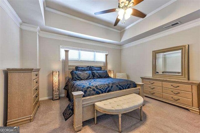 carpeted bedroom with a tray ceiling, crown molding, and ceiling fan