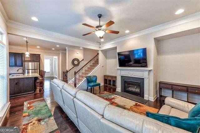 living room featuring ceiling fan, dark hardwood / wood-style floors, sink, and crown molding