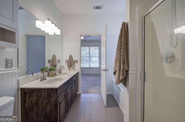 bathroom with tile patterned flooring, a shower with shower door, vanity, and toilet