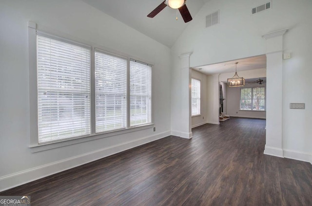 spare room with ceiling fan with notable chandelier, dark hardwood / wood-style floors, and high vaulted ceiling