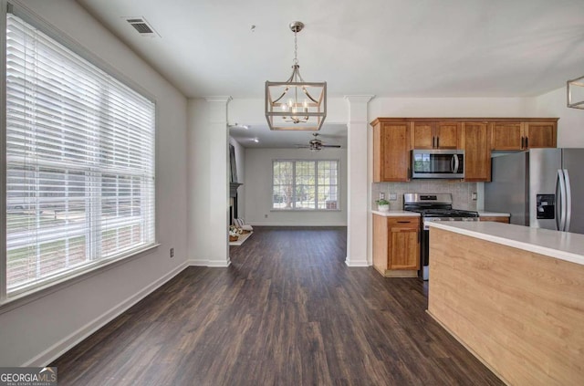 kitchen featuring decorative backsplash, pendant lighting, ceiling fan with notable chandelier, stainless steel appliances, and dark hardwood / wood-style floors