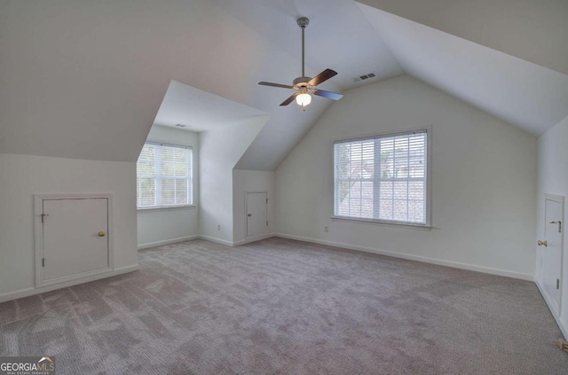 additional living space with lofted ceiling, light colored carpet, a wealth of natural light, and ceiling fan