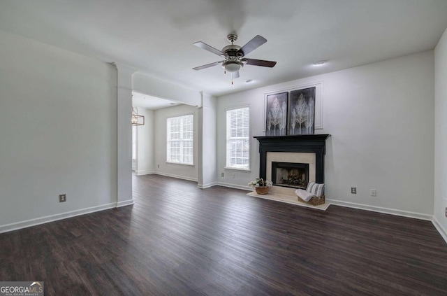 unfurnished living room featuring ceiling fan, a premium fireplace, and dark hardwood / wood-style flooring