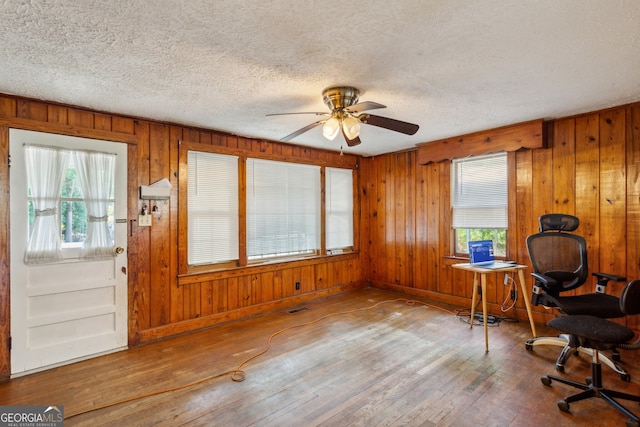 office space with wooden walls, hardwood / wood-style floors, and ceiling fan