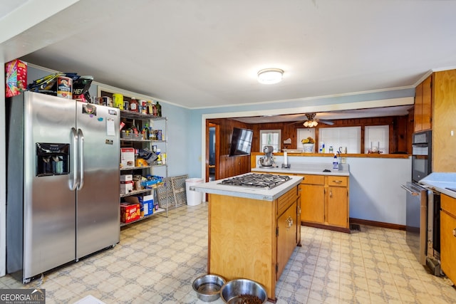 kitchen featuring stainless steel appliances, ceiling fan, crown molding, and a kitchen island