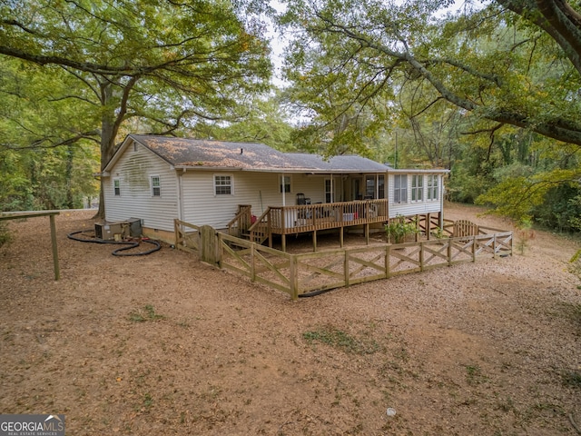 rear view of house featuring a sunroom and a deck