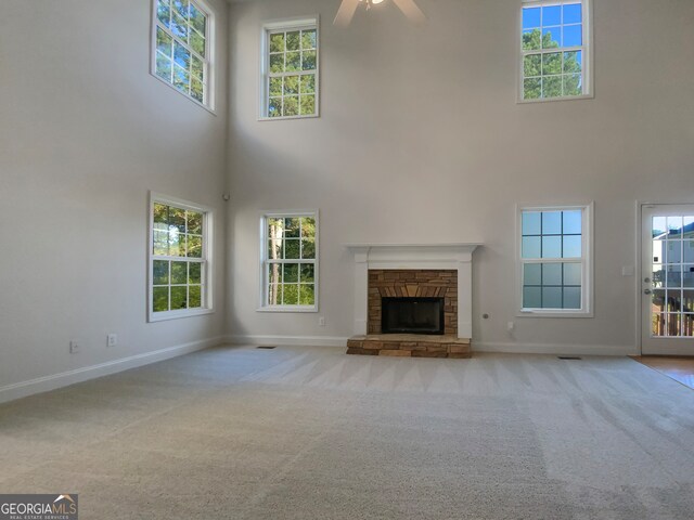 unfurnished living room featuring light carpet, plenty of natural light, and a high ceiling