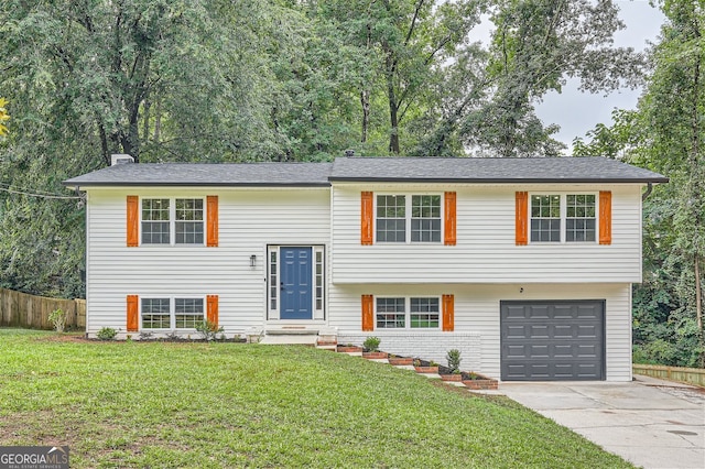 raised ranch featuring a garage and a front lawn