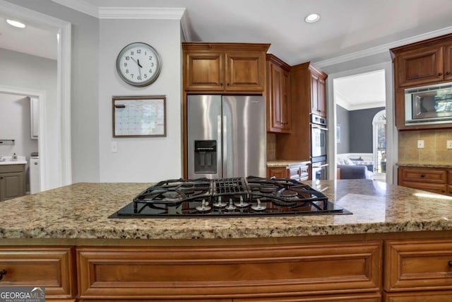 kitchen featuring stainless steel appliances, light stone countertops, ornamental molding, and decorative backsplash