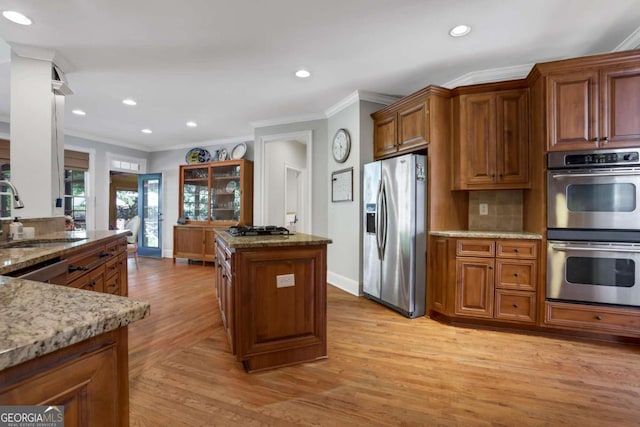 kitchen featuring appliances with stainless steel finishes, light hardwood / wood-style floors, sink, and ornamental molding