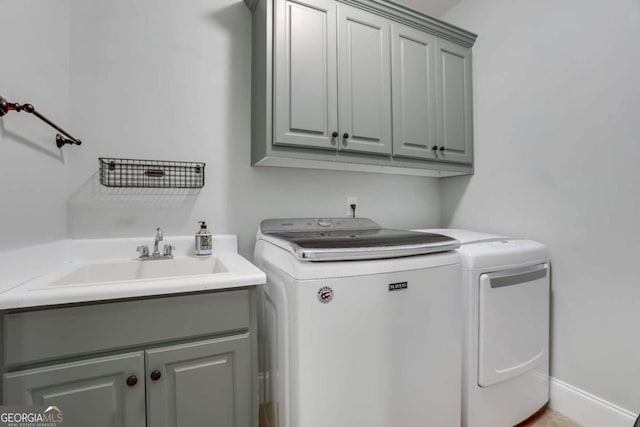 clothes washing area featuring cabinets, sink, and washing machine and clothes dryer