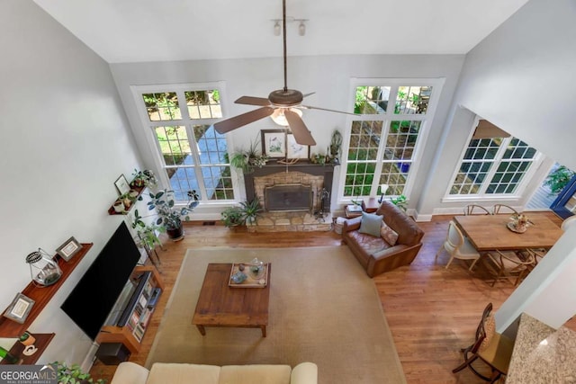 living room with ceiling fan, a fireplace, a wealth of natural light, and light hardwood / wood-style flooring