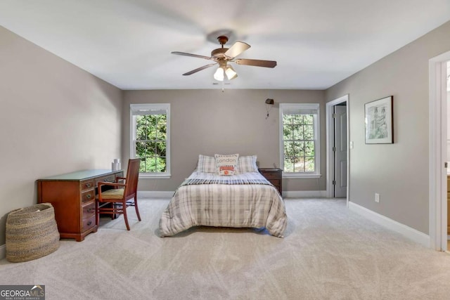 bedroom with ceiling fan, light carpet, and multiple windows