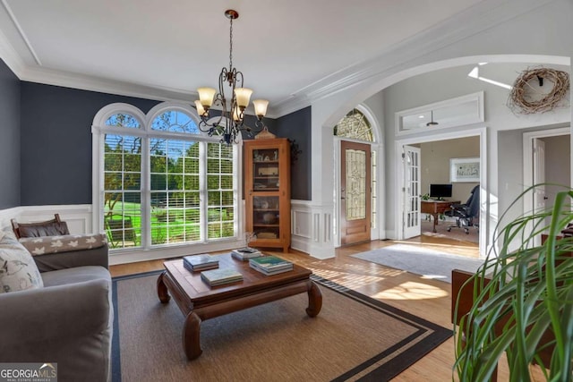 living room with light wood-type flooring, crown molding, and an inviting chandelier