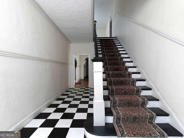 stairs with a textured ceiling and crown molding