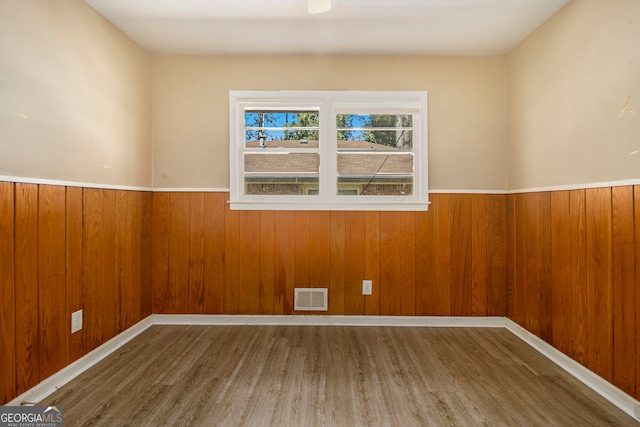 empty room with wooden walls and wood-type flooring