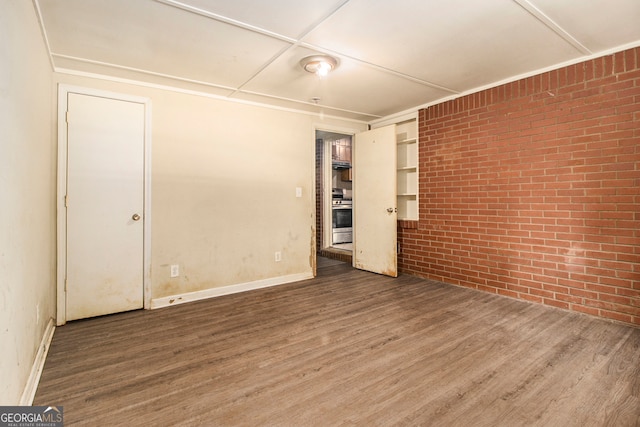 unfurnished room with brick wall and dark hardwood / wood-style floors