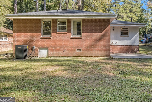 back of property with central air condition unit and a lawn