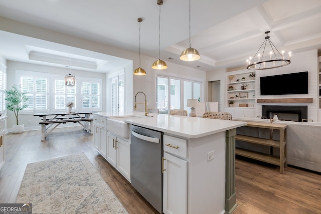 kitchen featuring a kitchen island with sink, stainless steel dishwasher, hanging light fixtures, and a wealth of natural light