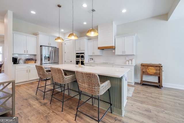 kitchen featuring pendant lighting, stainless steel appliances, light wood-type flooring, and white cabinets