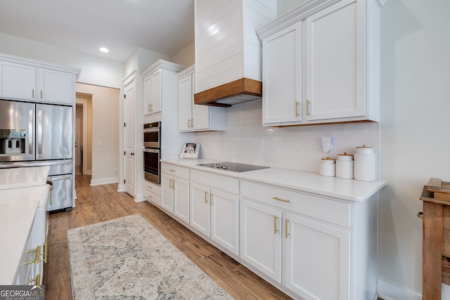 kitchen with appliances with stainless steel finishes, custom exhaust hood, white cabinets, and light wood-type flooring