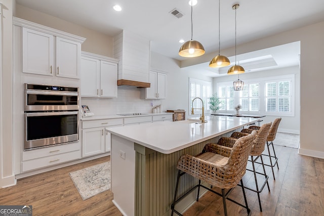 kitchen featuring a breakfast bar area, white cabinets, and an island with sink