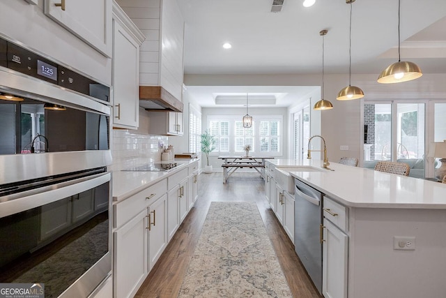 205 Park Chase, Pooler, GA 31322 - kitchen featuring stainless steel appliances, a tray ceiling, wood finished floors, light countertops, and a sink