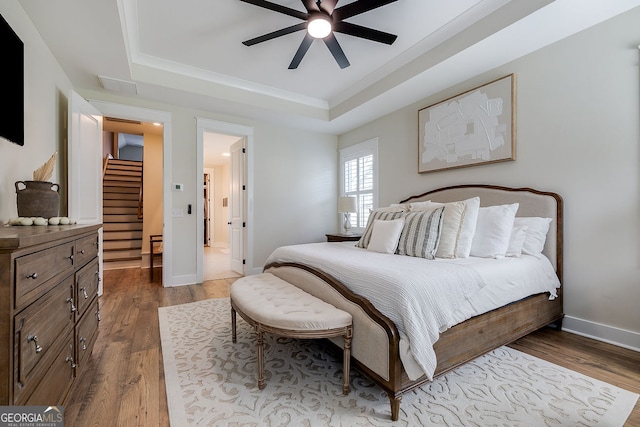 bedroom with dark wood-type flooring, ceiling fan, and a raised ceiling