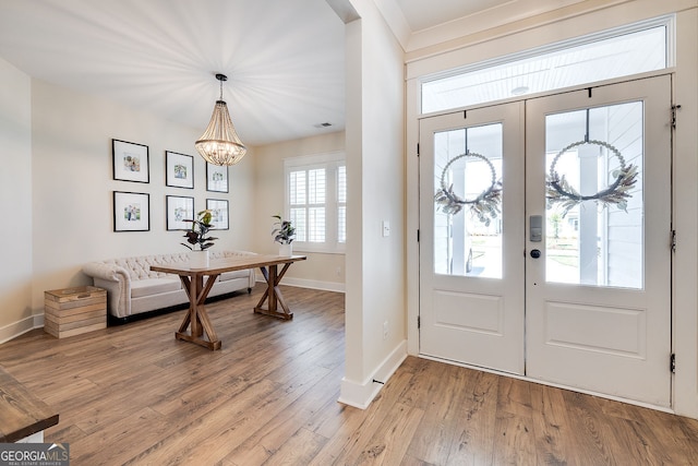 foyer with an inviting chandelier, a healthy amount of sunlight, and light wood-type flooring