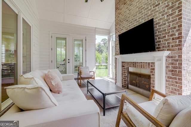 interior space featuring french doors, an outdoor brick fireplace, vaulted ceiling, and plenty of natural light