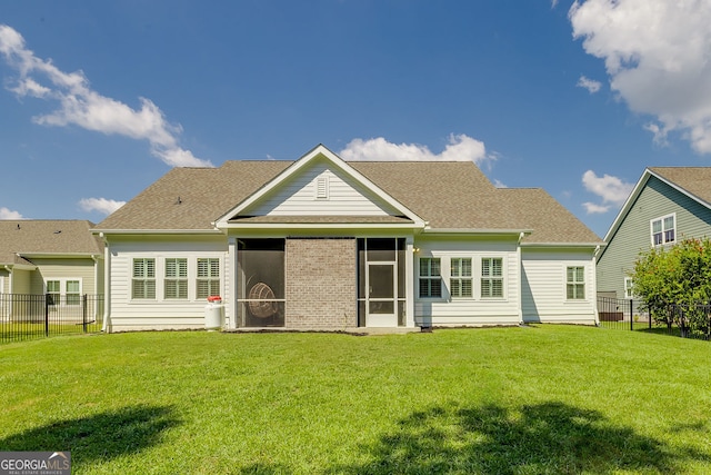 rear view of property featuring a yard and a sunroom