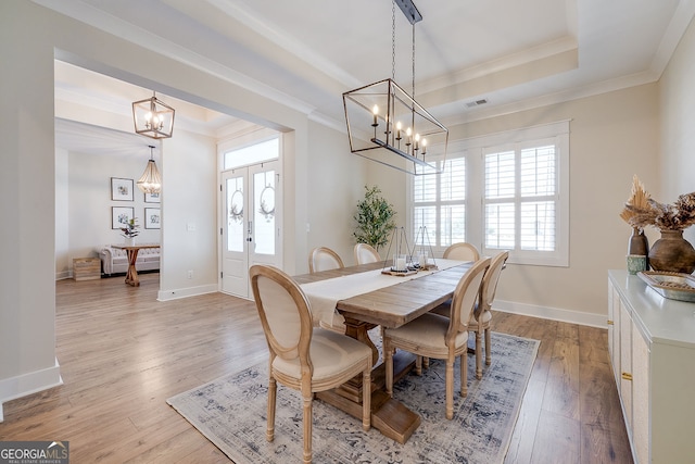 dining area featuring light hardwood / wood-style floors, french doors, ornamental molding, and an inviting chandelier