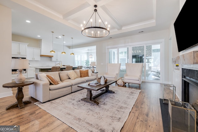 living room with light hardwood / wood-style flooring, a chandelier, beamed ceiling, and coffered ceiling