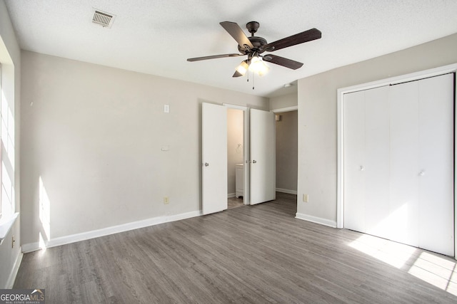 unfurnished bedroom with a closet, a textured ceiling, hardwood / wood-style flooring, and ceiling fan