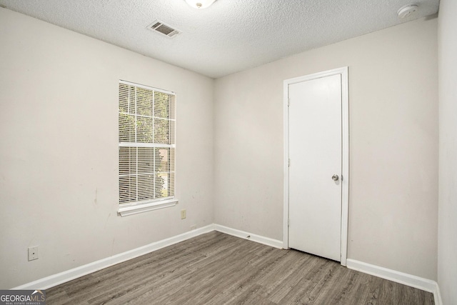 unfurnished room with hardwood / wood-style floors and a textured ceiling