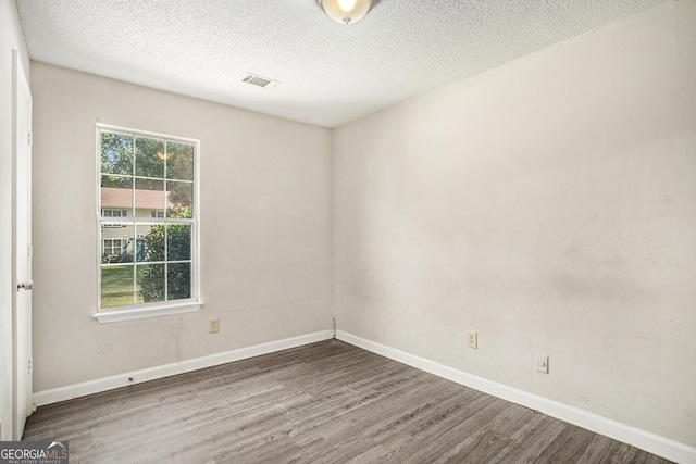 unfurnished room with a textured ceiling and dark hardwood / wood-style flooring