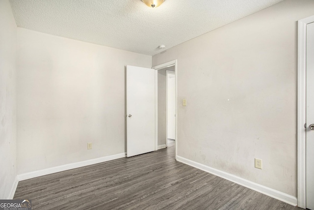 unfurnished room with a textured ceiling and dark hardwood / wood-style floors