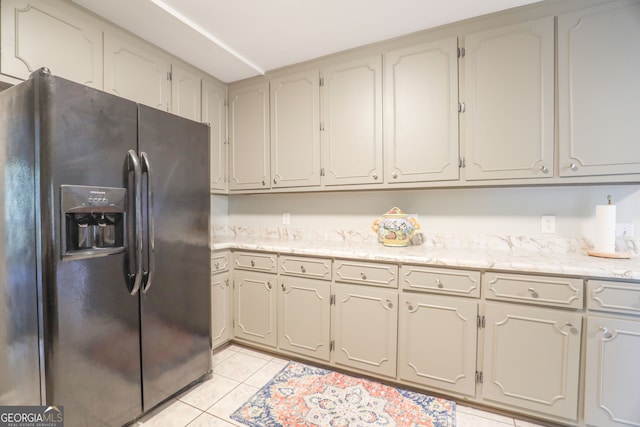 kitchen featuring black fridge and light tile patterned flooring