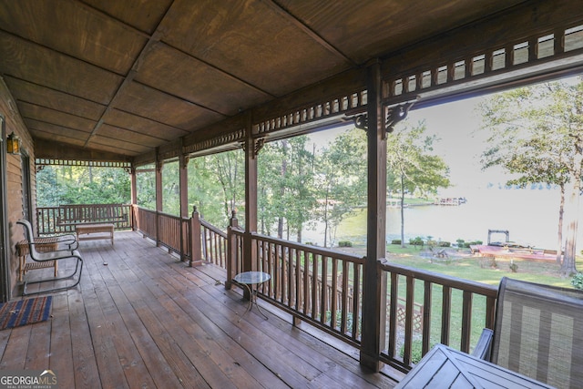 wooden deck with a lawn and a water view