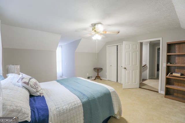 carpeted bedroom featuring a closet, vaulted ceiling, a textured ceiling, and ceiling fan