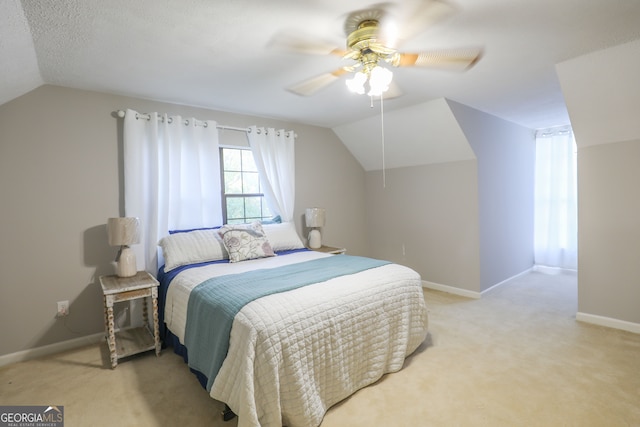 bedroom featuring lofted ceiling, light colored carpet, a textured ceiling, and ceiling fan