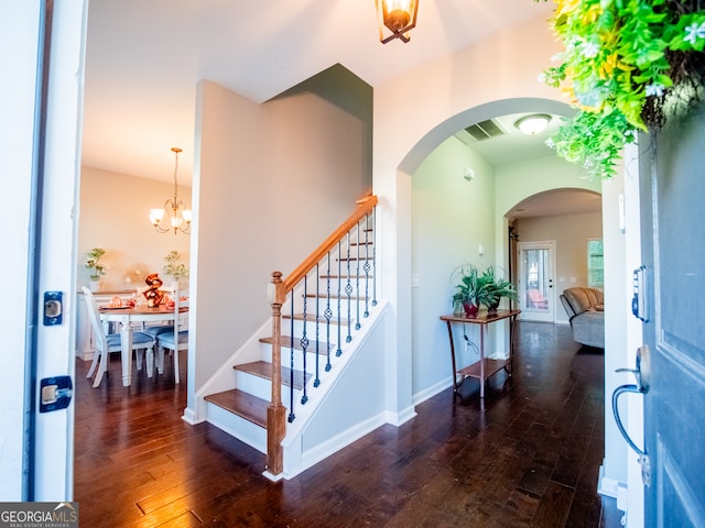 entrance foyer with dark hardwood / wood-style flooring and a notable chandelier