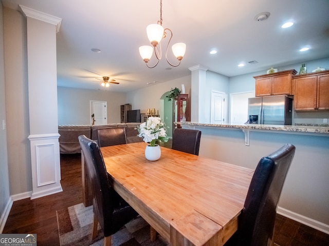 dining room with ceiling fan with notable chandelier, dark hardwood / wood-style floors, and decorative columns