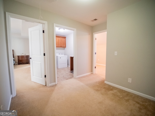 corridor with washer / clothes dryer and light colored carpet