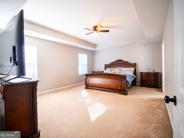 bedroom featuring ceiling fan, a raised ceiling, and light carpet