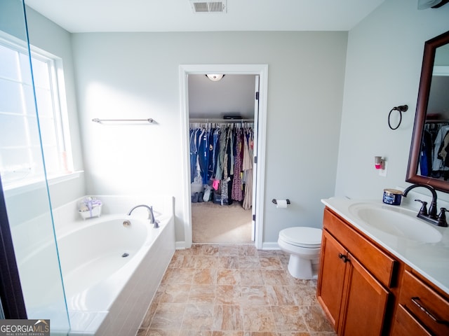 bathroom with toilet, tiled tub, and vanity